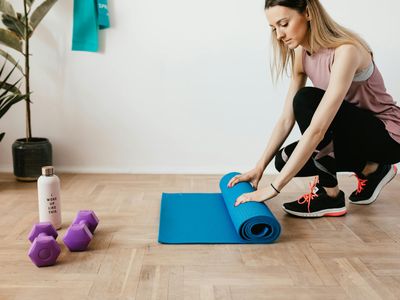 Close up of a yoga mat and water bottle on wooden floor.
